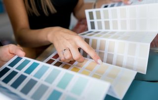 Close-up of two women choosing samples of wall paint. Interior designer consulting a client looking at a color swatch. House renovation concept Psychology of Paint Colors in Interior Design, color of the year