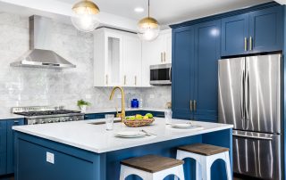 A luxurious white and blue kitchen with gold hardware, stainless steel appliances, and white marbled granite counter tops. protect painted cabinets