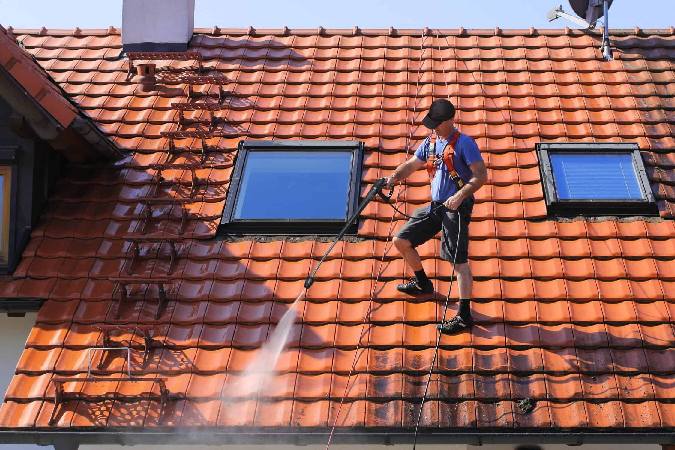 Worker is cleaning the roof and rainwater gutter with high pressure.